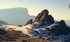 there is a mountain with snow on the ground and rocks in the foreground,