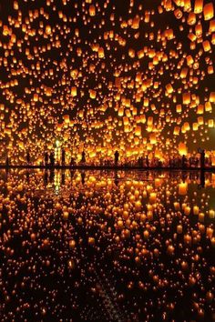 people are standing in front of many lit up lanterns that look like they have been floating