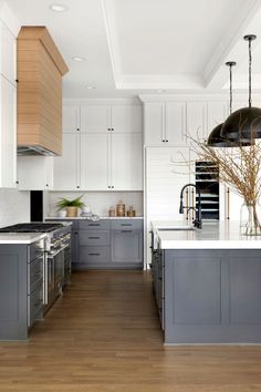 a large kitchen with white cabinets and gray counter tops, along with wooden flooring