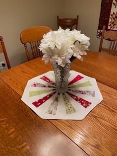 a vase filled with white flowers sitting on top of a wooden table