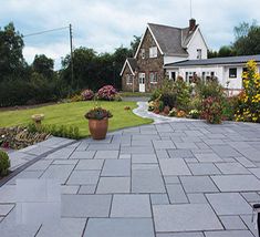 a large patio with potted plants and flowers on the ground in front of a house