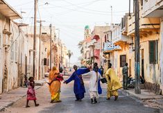 several people are walking down the street in an alley way, one is holding onto another person's hand