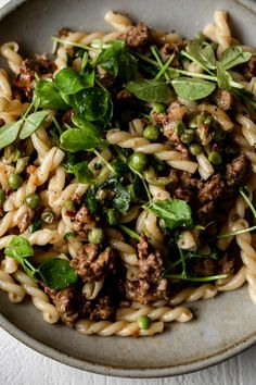 pasta with meat, peas and spinach in a bowl on a white tablecloth