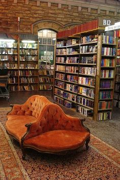 an orange couch sitting in front of a library filled with books