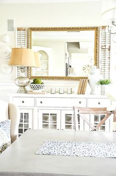 a dining room table with chairs and a mirror on the wall