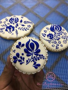 three decorated cookies sitting on top of a blue and white tablecloth covered trays