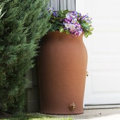 a large potted planter sitting next to a door with purple flowers in it