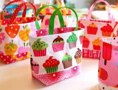 colorful bags with cupcakes on them are sitting on a table in front of other items