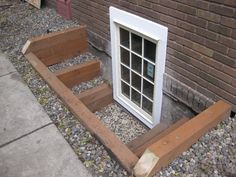 a window sitting on the side of a brick building next to a wooden bench and steps