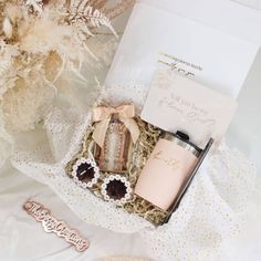 an open box with some items in it on a white surface next to a bouquet