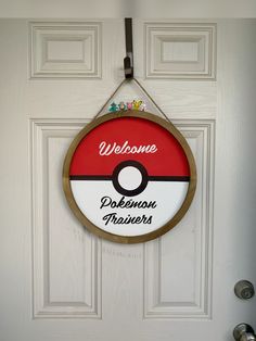 a welcome sign hanging on the front door to a house with a pokeball theme