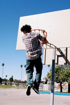 a young man jumping up into the air on top of a basketball hoop with his feet in the air