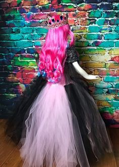 a pink and black dress with a tiara on the head is next to a brick wall