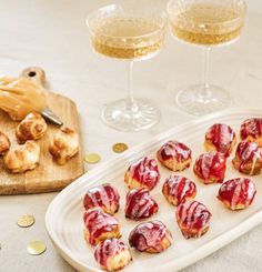 small pastries on a plate next to two glasses of wine