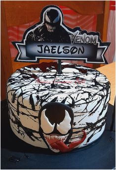 a birthday cake decorated with an image of a demon and nameplate that says venom