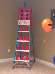 a ladder that has red cups on it and a balloon in the air next to it