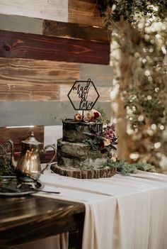 a wedding cake sitting on top of a table next to a wooden sign that says mr and mrs