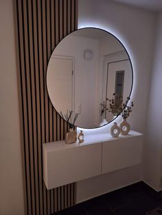 a mirror sitting on top of a white counter next to a vase filled with flowers