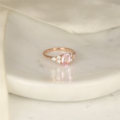 a pink diamond ring sitting on top of a white plate