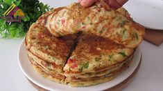 a stack of pancakes sitting on top of a white plate next to a green plant