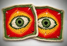 two crocheted coasters made to look like eyeballs on red, yellow and green