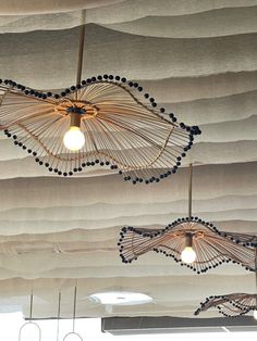 several lights hanging from the ceiling in a room with wavy paper coverings on it