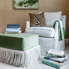 a living room with a chair, ottoman and books on the floor in front of it