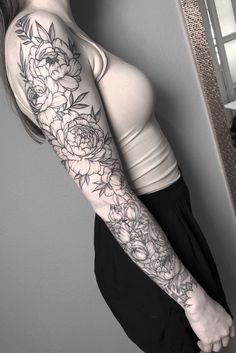 a woman with a flower tattoo on her arm is standing in front of a mirror