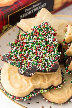 christmas cookies with sprinkles on a plate next to a box of shortbread