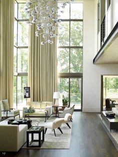 a living room filled with lots of furniture and a chandelier hanging from the ceiling