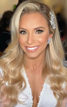 a woman with long blonde hair wearing a tiara and smiling at the camera while sitting down