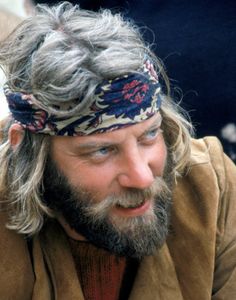 a man with long hair and a bandana on his head looking at something off to the side