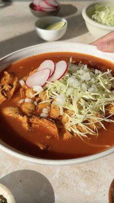 a bowl filled with soup and garnishes on top of a table next to other bowls