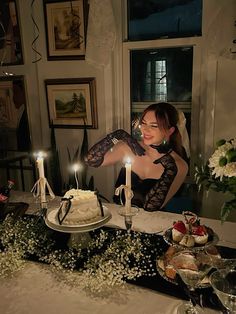 a woman sitting at a table in front of a cake with lit candles on it