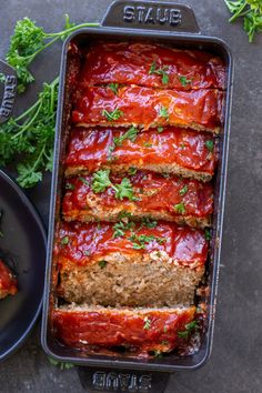 meatloaf with marinara sauce and parsley in a pan next to a plate