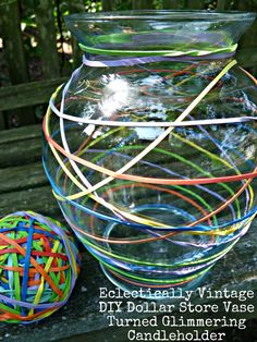 a glass vase filled with colorful rubber bands next to a ball of yarn on a wooden bench