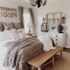 a bed sitting in a bedroom under a chandelier next to a wooden bench