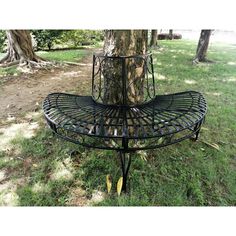 a metal bench sitting in the grass next to a tree