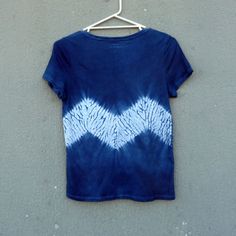 a blue and white tie dye shirt hanging on a hanger against a gray wall