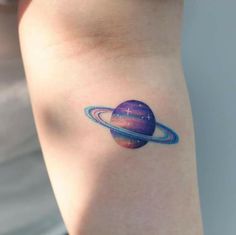 a small saturn tattoo on the arm