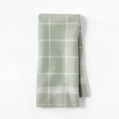 a green and white checkered napkin folded on top of a white wall with a black tie