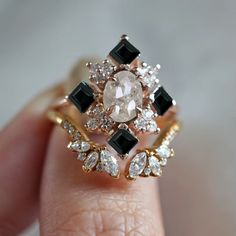 a close up of a person's hand holding an engagement ring with black and white stones