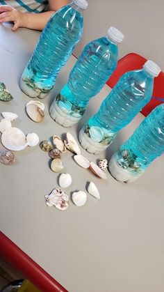 several bottles of water sitting on top of a table next to seashells and shells