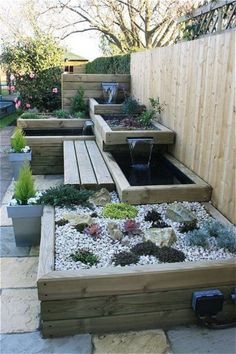 a wooden bench sitting next to a garden filled with lots of plants and rocks on top of