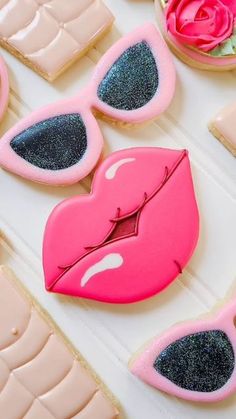 decorated cookies with pink lips and sunglasses on top of a white countertop next to macaroni and cheese