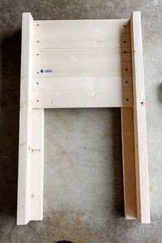 a wooden bench sitting on top of a cement floor next to a pair of black shoes