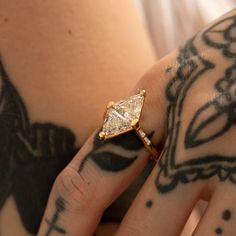 a close up of a person's hand wearing a ring with a diamond on it