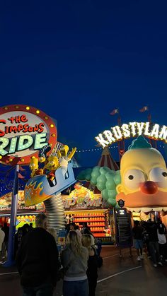 people are walking around an amusement park at night