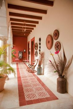 a red and white hallway with pictures on the wall, potted plants and chairs