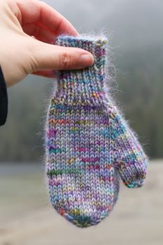 a hand holding up a knitted mitt